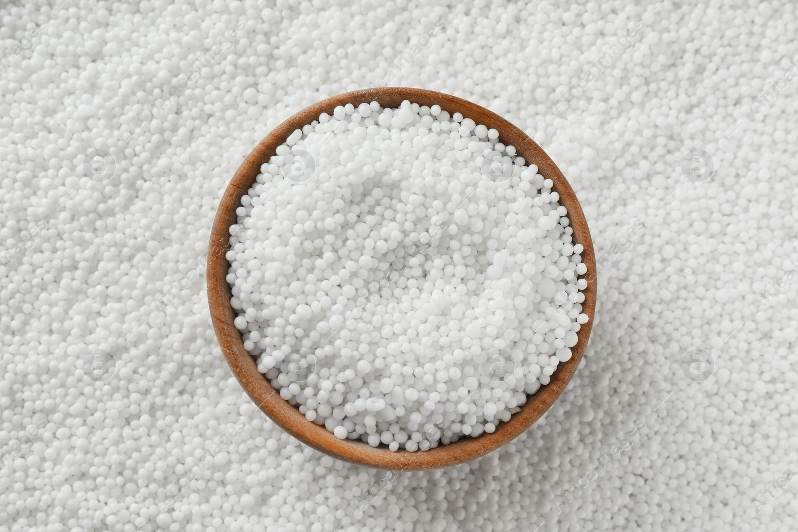 Photo of Bowl on pellets of ammonium nitrate, top view. Mineral fertilizer