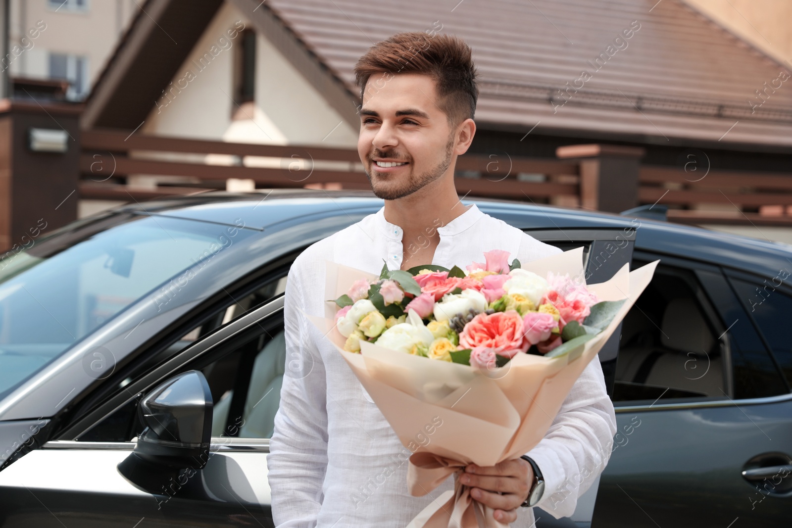 Photo of Young handsome man with beautiful flower bouquet near car outdoors