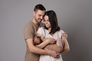 Happy family. Couple with their sleeping baby on grey background