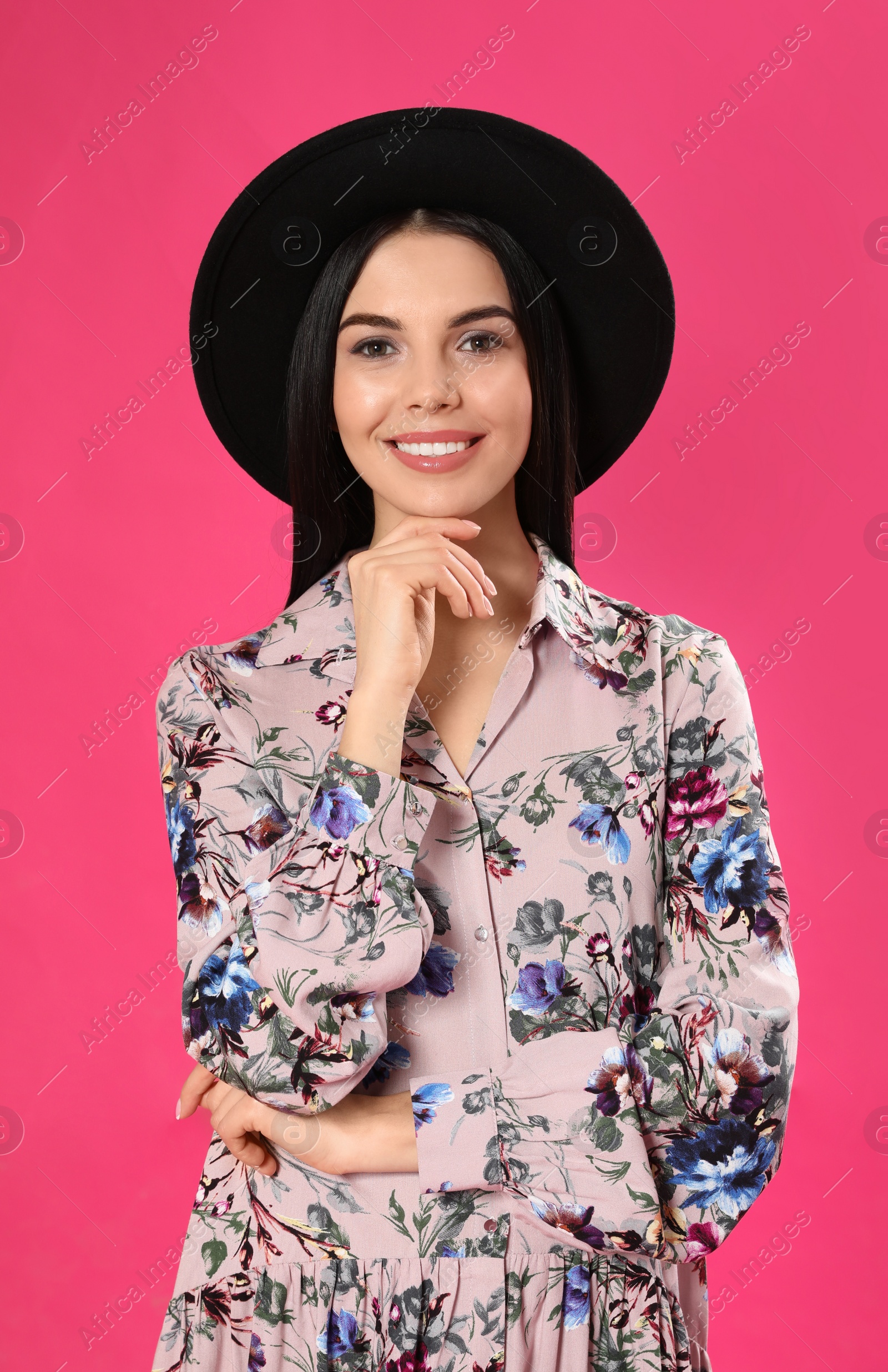 Photo of Young woman wearing floral print dress and stylish hat on pink background