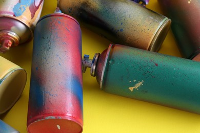 Photo of Many spray paint cans on yellow background