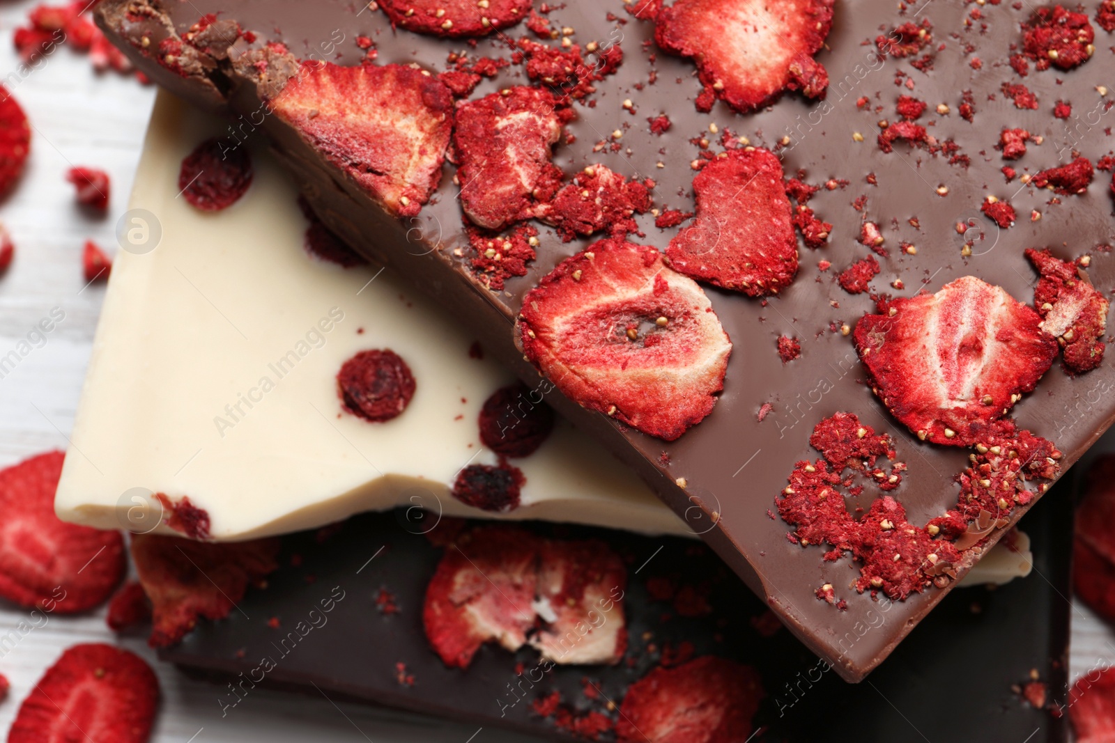 Photo of Different chocolate bars with freeze dried fruits on table, closeup