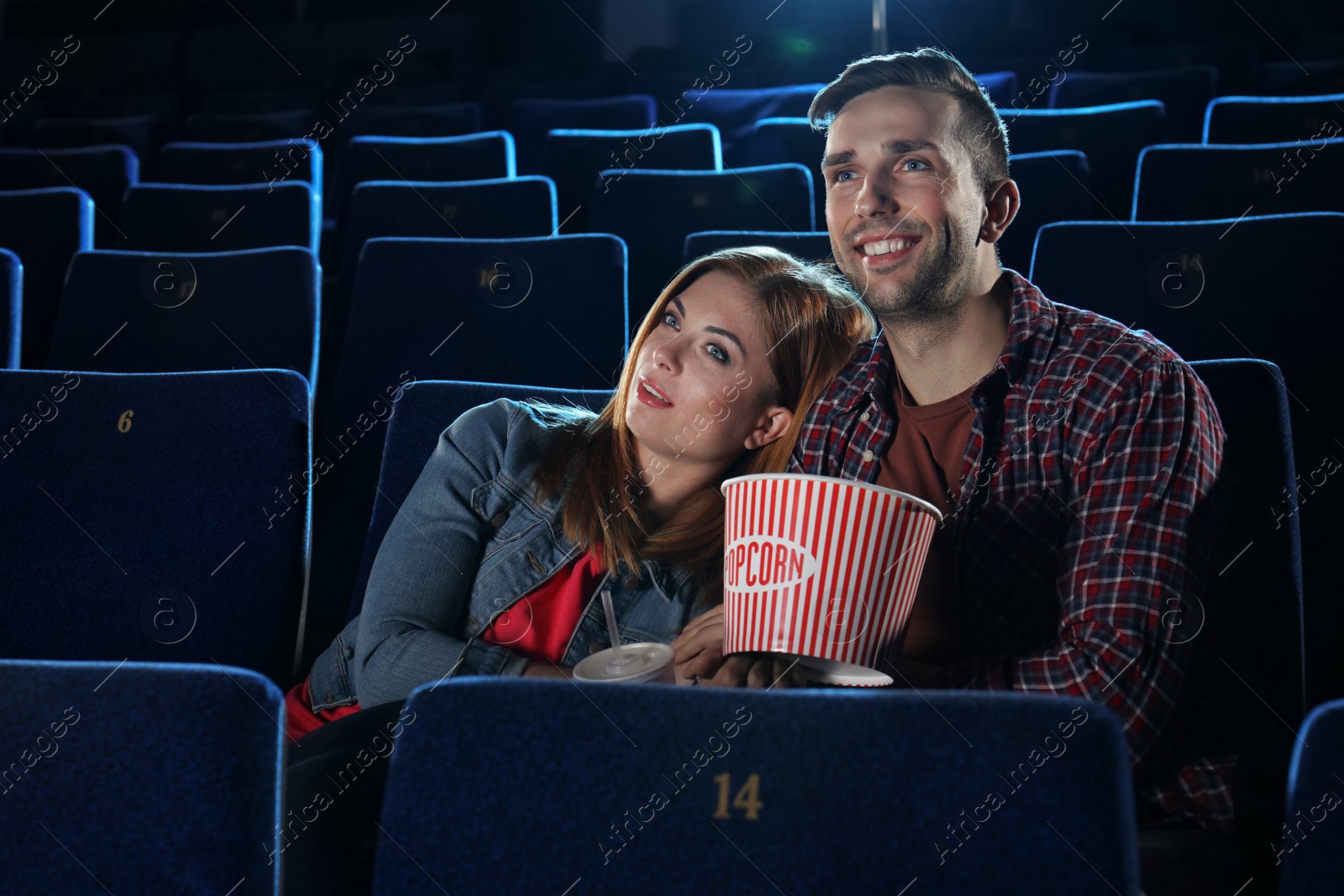 Photo of Young couple with popcorn watching movie in cinema theatre