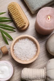 Photo of Flat lay composition with spa products and burning candle on light wooden table