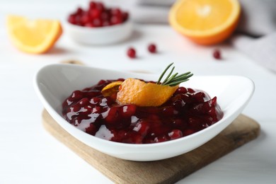 Photo of Fresh cranberry sauce, orange peel and rosemary in bowl on white table, closeup
