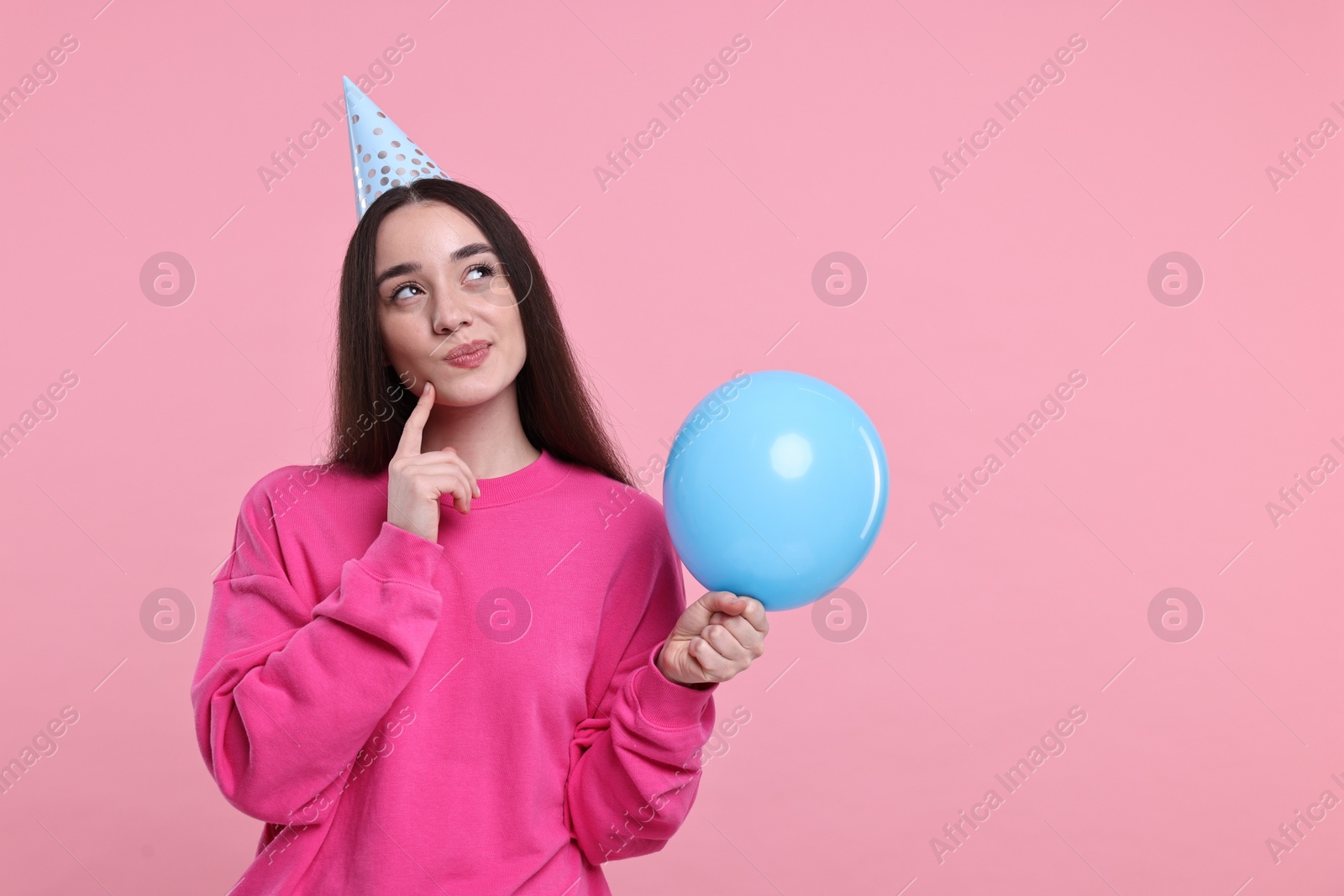 Photo of Woman in party hat with balloon on pink background, space for text