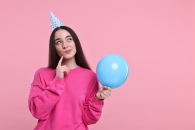 Photo of Woman in party hat with balloon on pink background, space for text