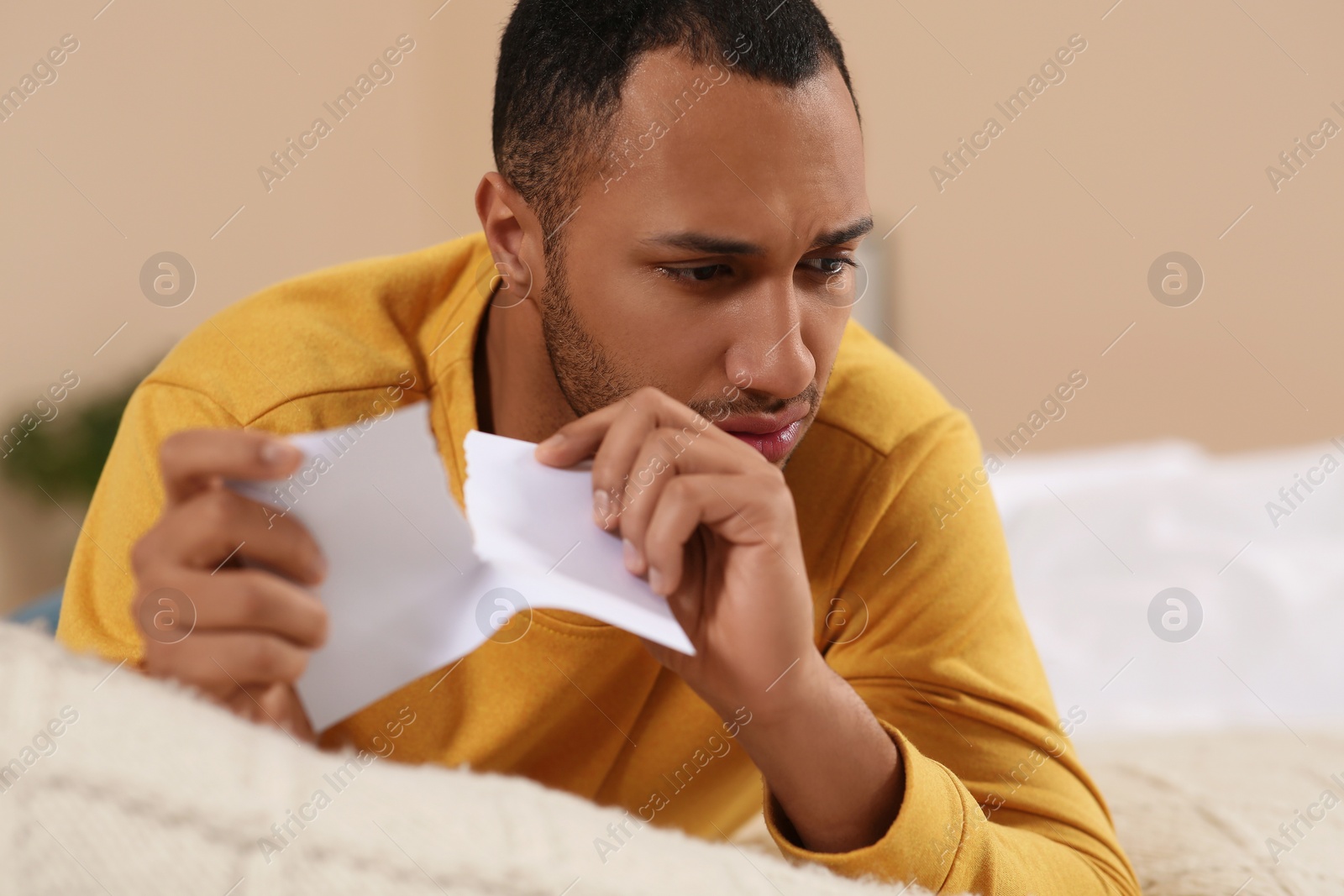 Photo of Upset African American man with torn photo indoors. Divorce concept