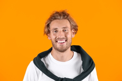 Photo of Handsome young man laughing on color background