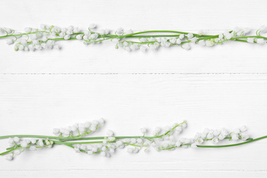 Beautiful lily of the valley flowers on white wooden table, flat lay. Space for text