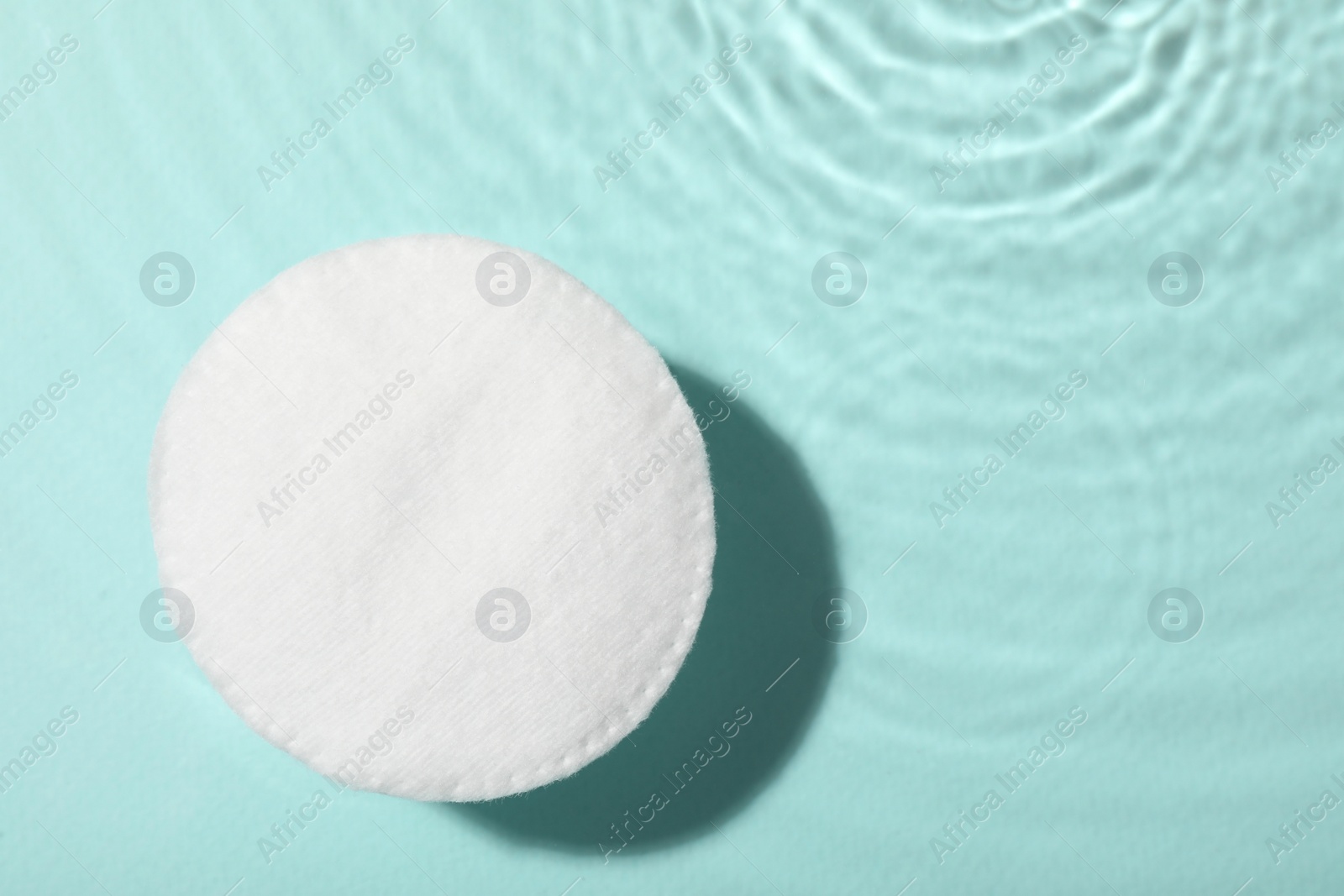 Photo of Cotton pad and micellar water on light blue background, top view. Space for text