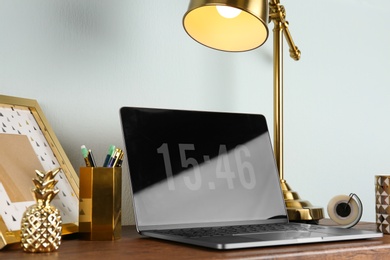 Photo of Modern workplace with laptop and golden decor on desk near wall. Stylish interior design