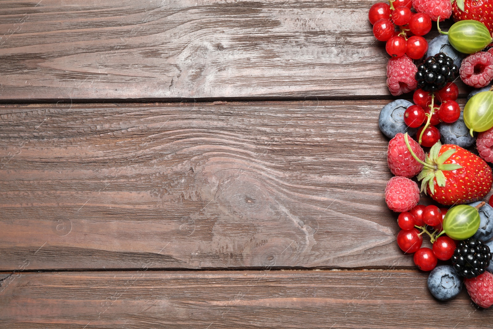 Photo of Different fresh berries on wooden table, flat lay. Space for text