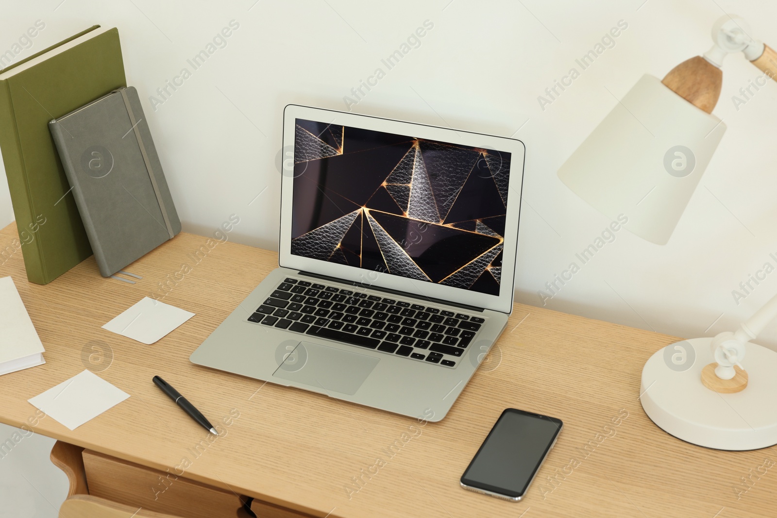 Photo of Cozy workspace with laptop, smartphone and lamp on wooden desk at home