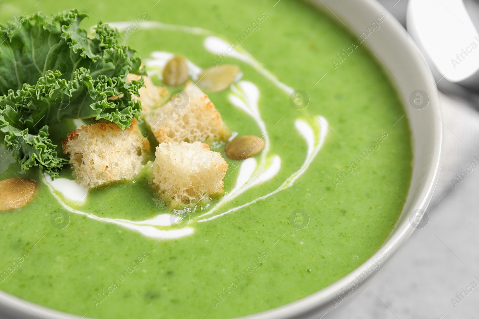 Photo of Tasty kale soup with croutons on table, closeup