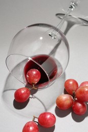 Overturned glass of wine and grapes on white background, closeup