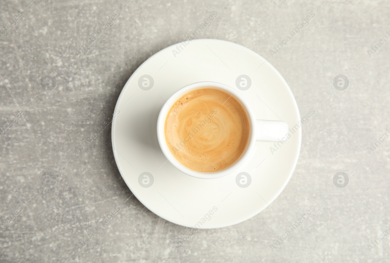 Photo of Cup of hot aromatic espresso on light table, top view