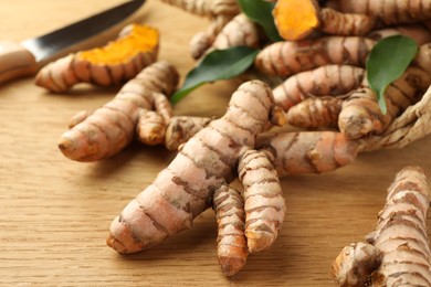 Photo of Many raw turmeric roots on wooden table, closeup