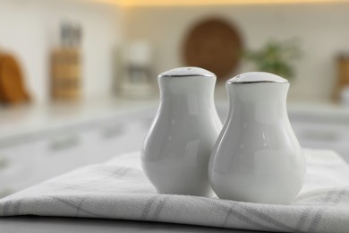 Photo of Ceramic salt and pepper shakers with napkin on table in kitchen. Space for text