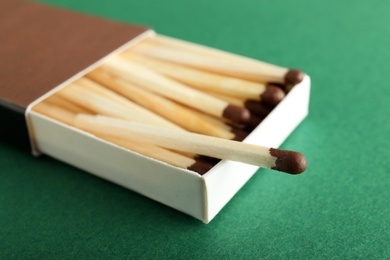 Photo of Open box with matches on color background, closeup