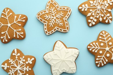 Photo of Tasty star shaped Christmas cookies with icing on light blue background, flat lay