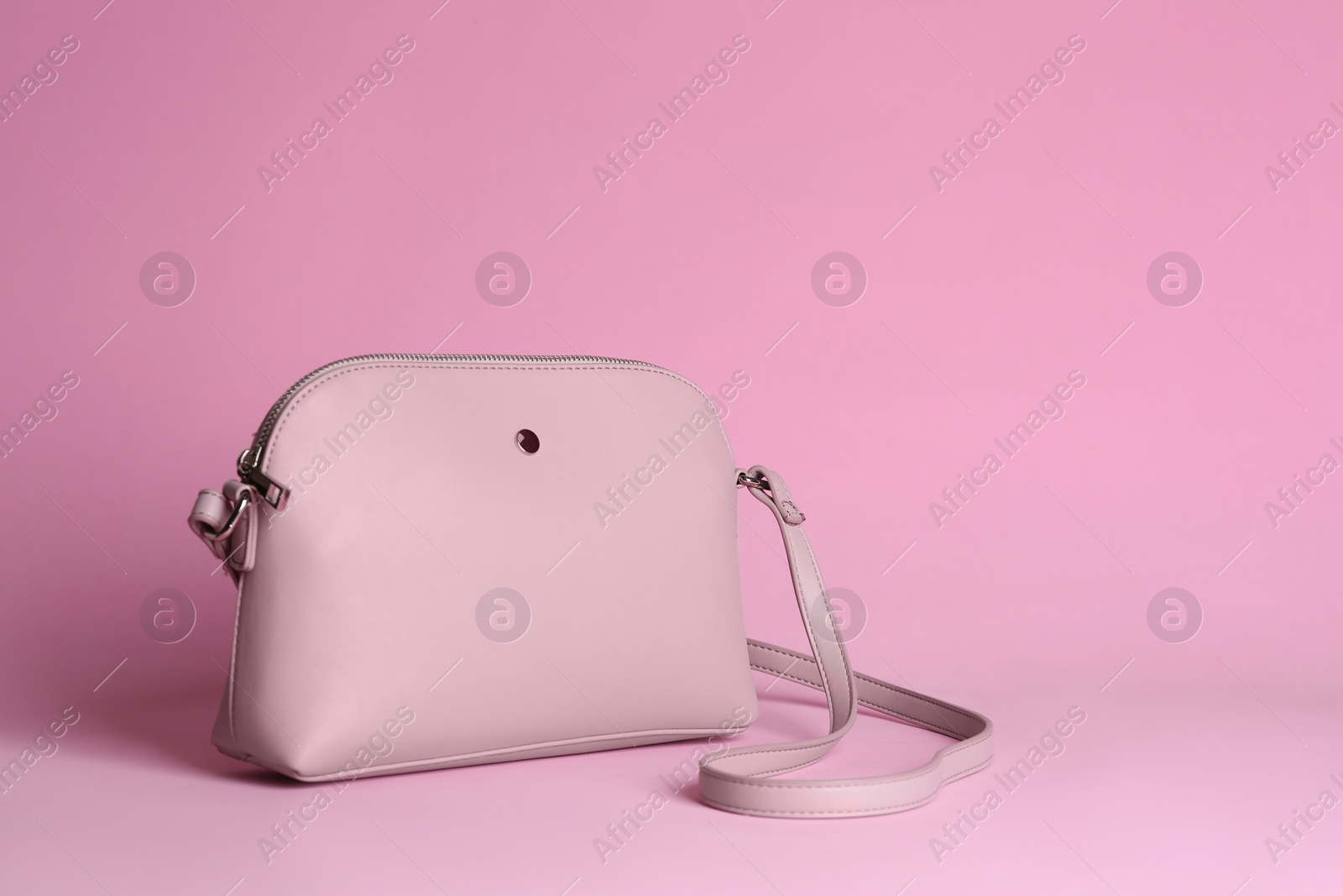 Photo of Stylish woman's bag on light pink background. Space for text
