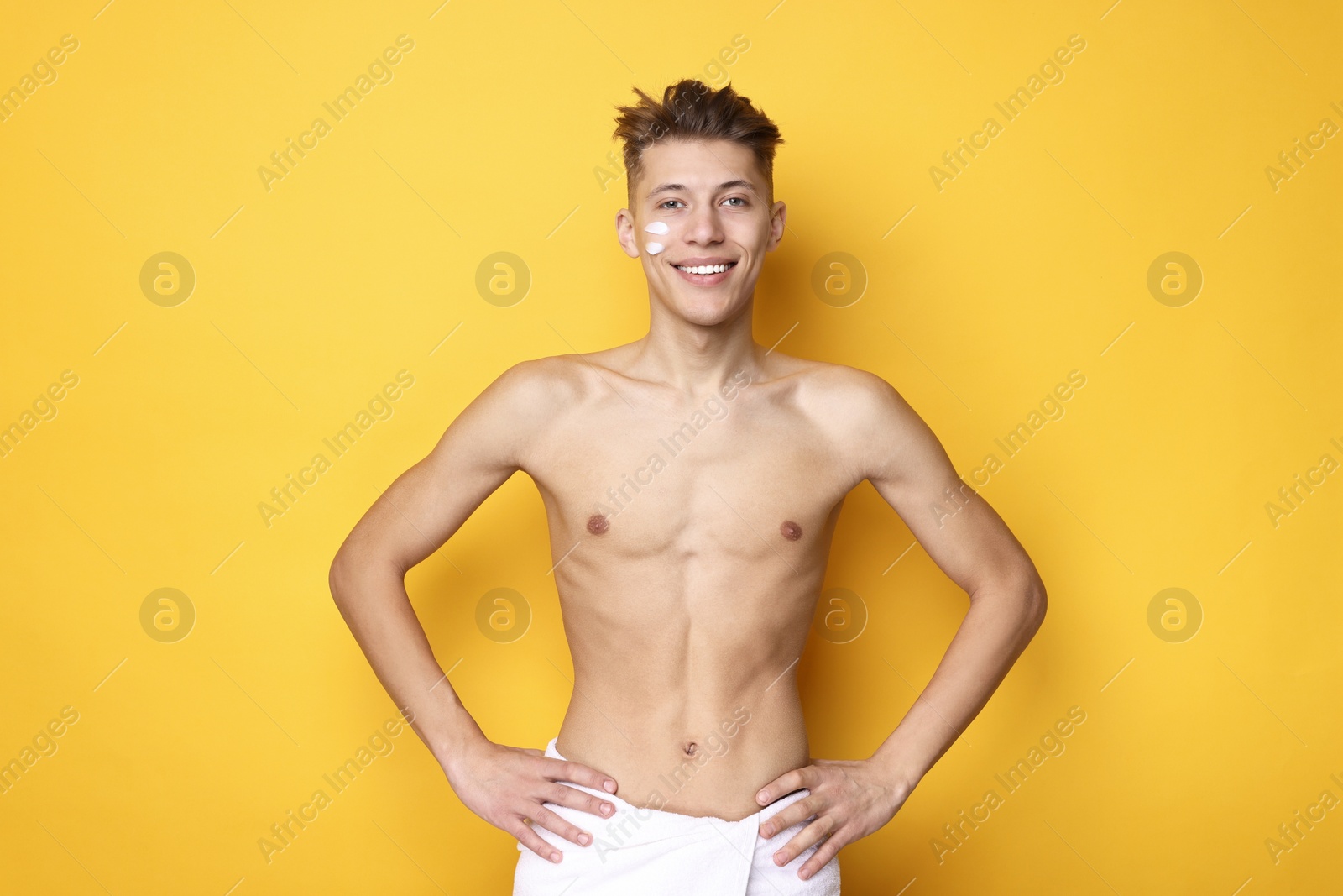 Photo of Handsome man with moisturizing cream on his face against orange background
