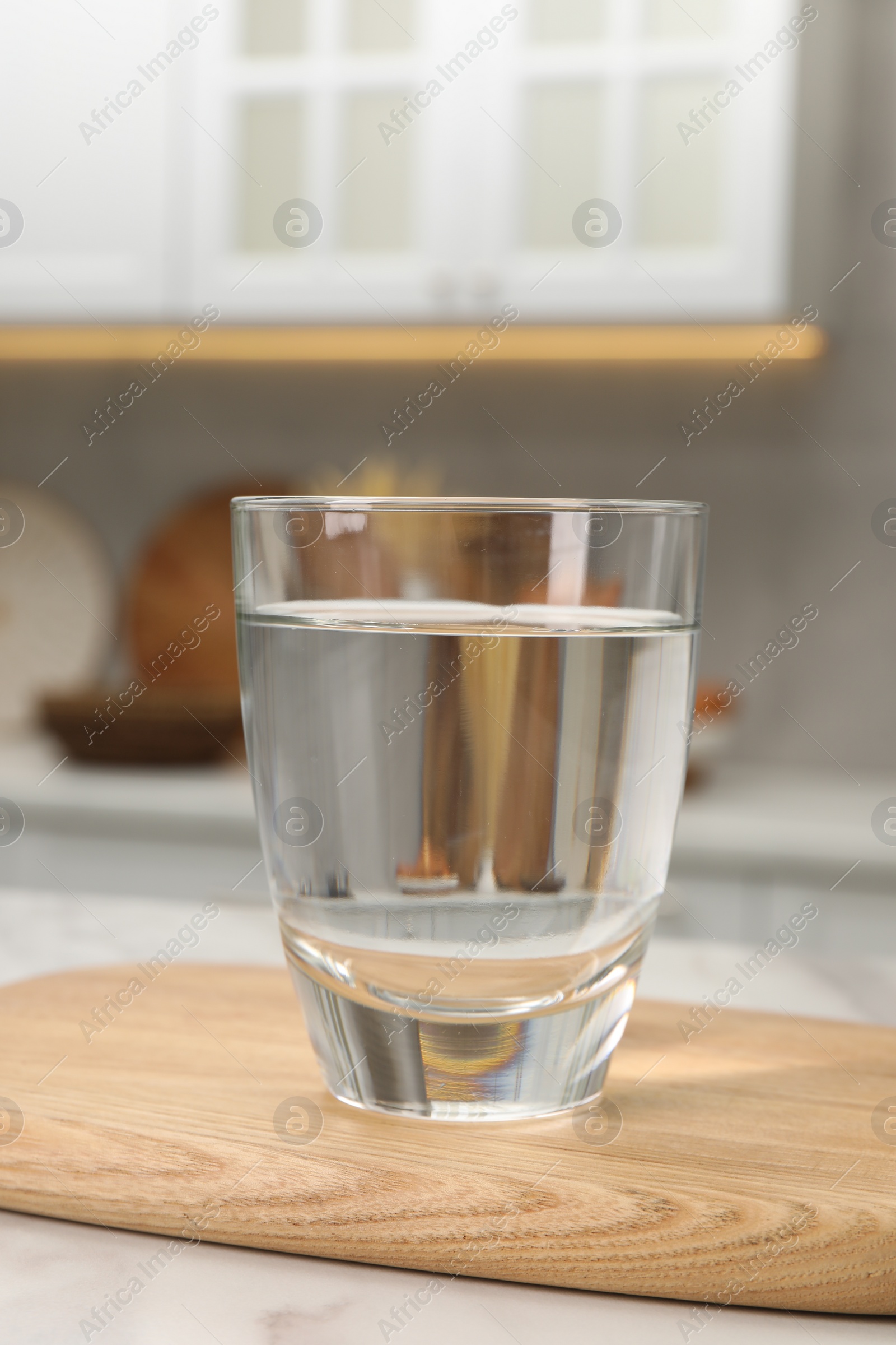 Photo of Filtered water in glass on white table in kitchen, closeup