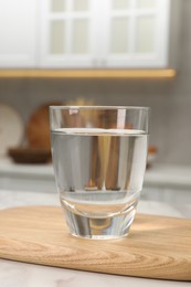 Filtered water in glass on white table in kitchen, closeup