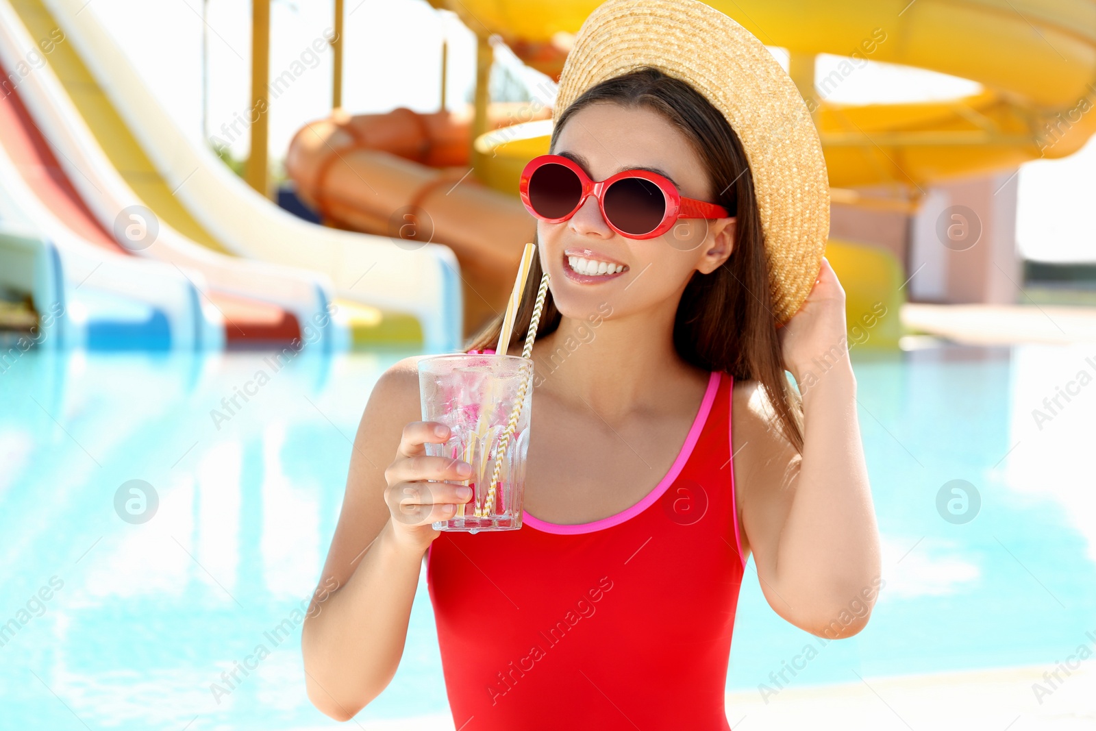 Photo of Woman with glass of refreshing drink in water park