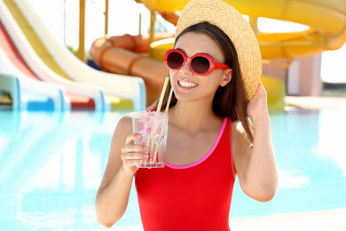 Photo of Woman with glass of refreshing drink in water park