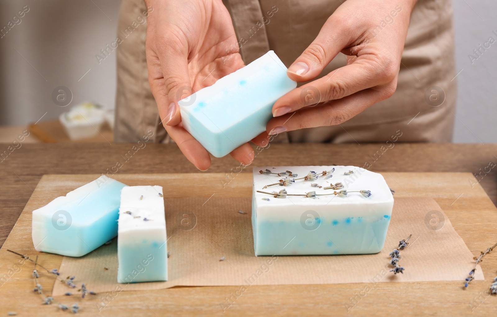 Photo of Woman with natural handmade soap at wooden table, closeup