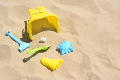Bright plastic bucket, rake and shovel on sand. Beach toys. Space for text