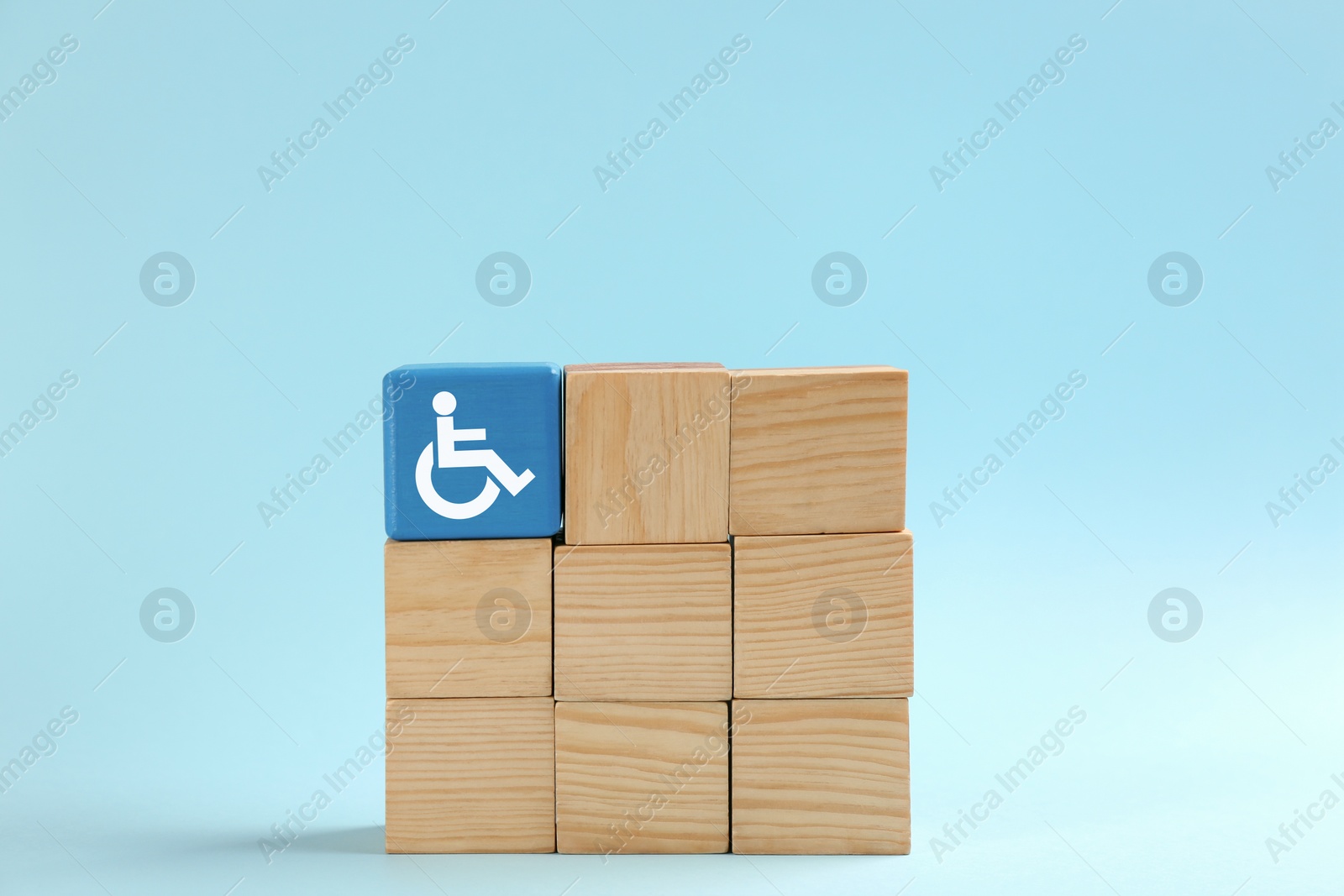 Image of Inclusion concept. One cube with international symbol of access among wooden ones on light blue background