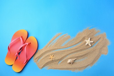 Photo of Flip flops and sand on light blue background, flat lay with space for text. Beach accessories