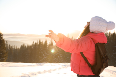 Photo of Happy young woman outdoors on snowy winter day. Space for text