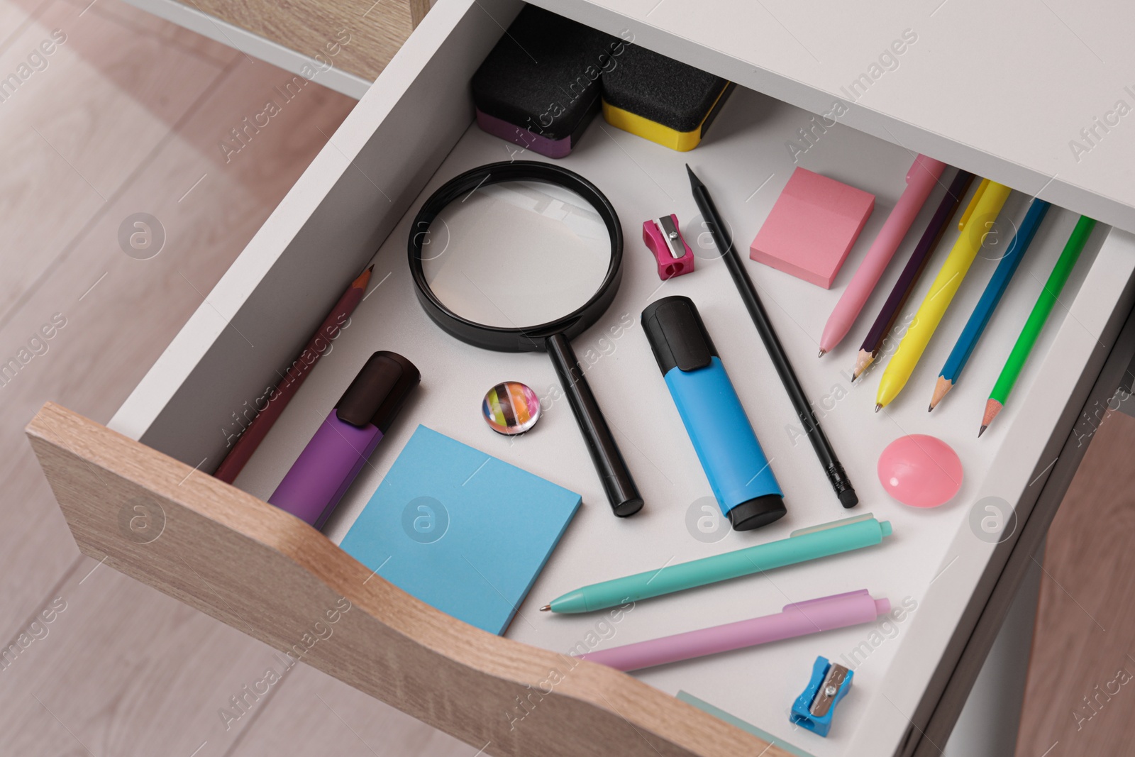 Photo of Office supplies in open desk drawer, above view