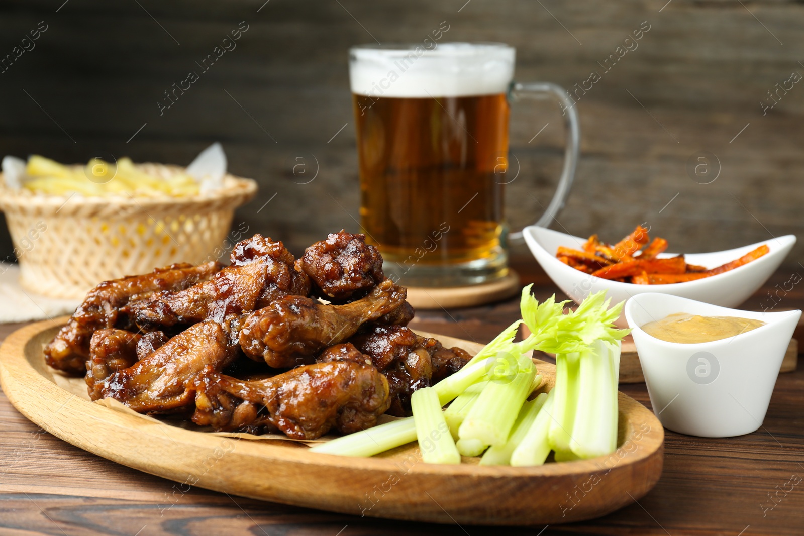 Photo of Delicious chicken wings served with beer on wooden table, closeup
