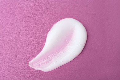 Sample of hand cream on pink background, top view