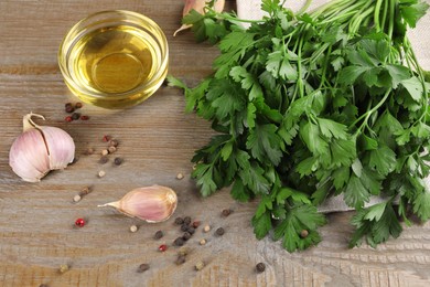 Bunch of raw parsley, oil, garlic and peppercorns on wooden table, closeup