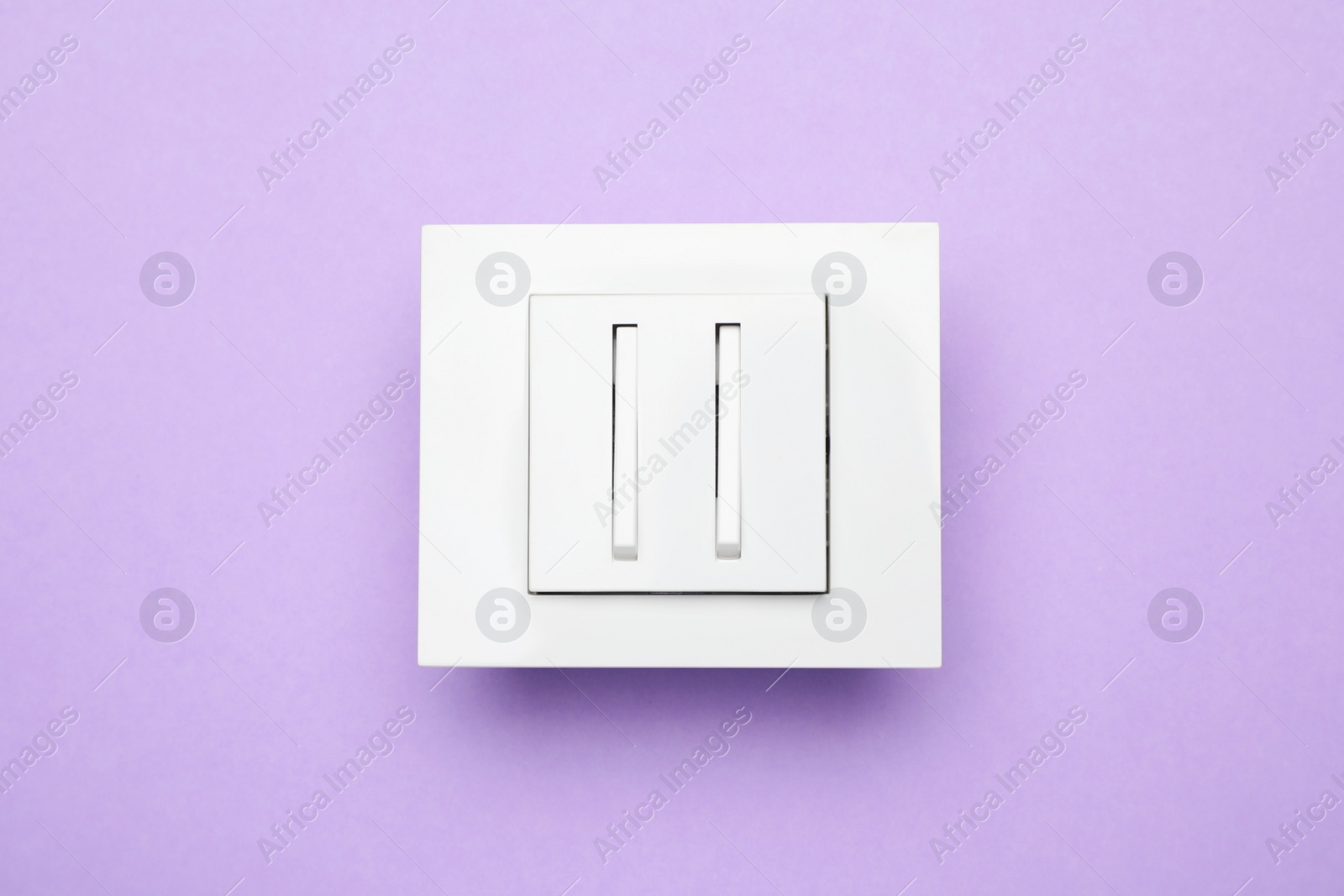 Photo of White light switch on violet background, top view