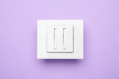 Photo of White light switch on violet background, top view