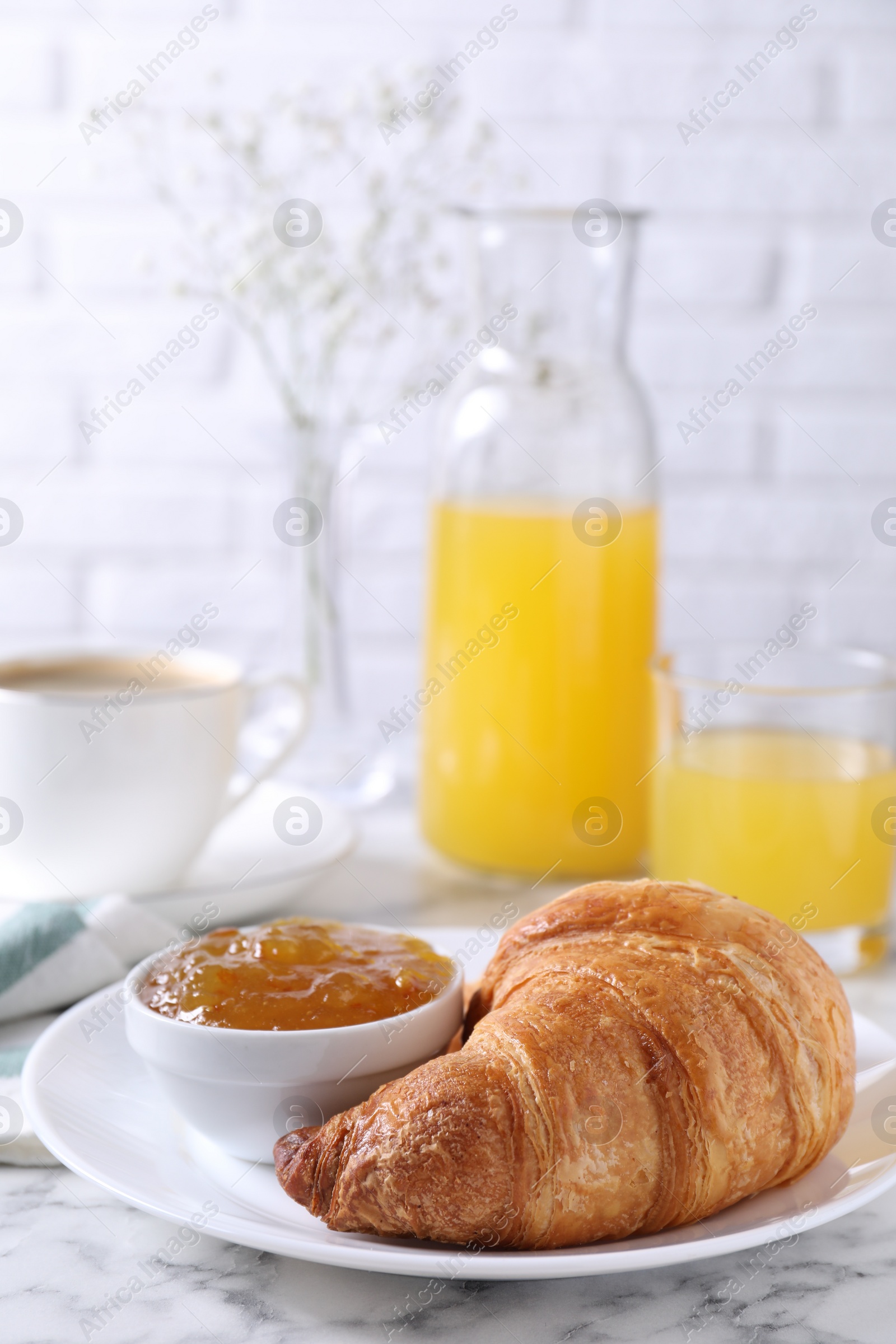 Photo of Tasty breakfast. Fresh croissant and jam on white marble table