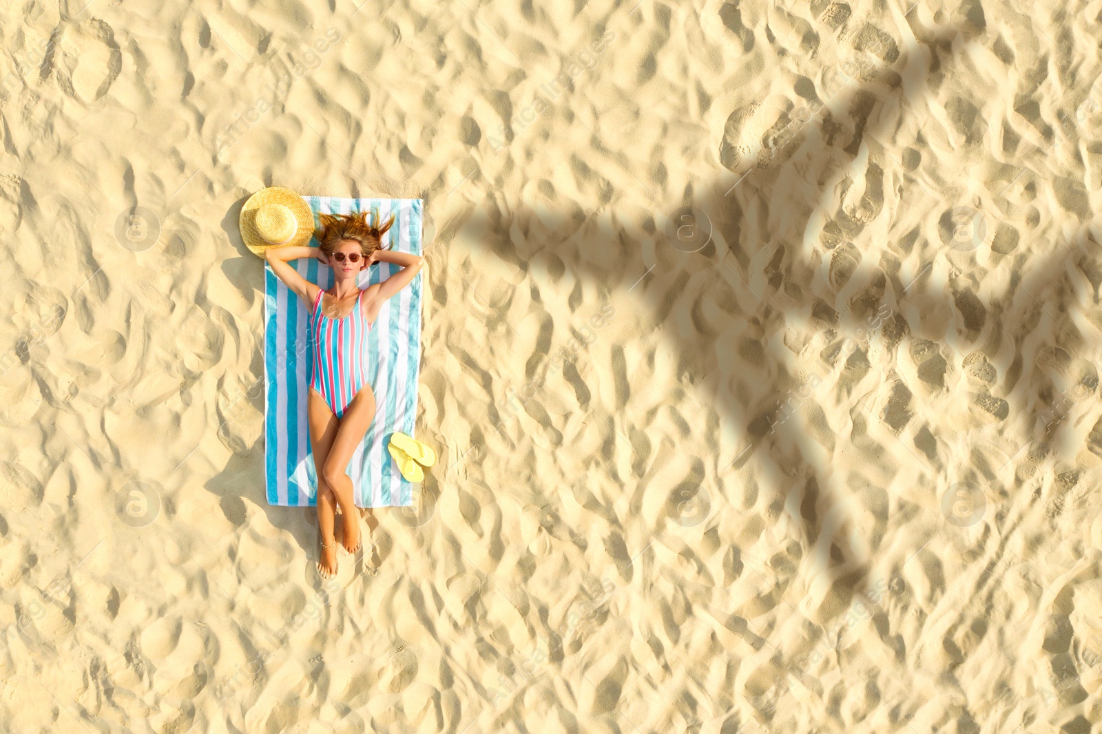 Image of Shadow of airplane and woman sunbathing at sandy beach, aerial view. Summer vacation