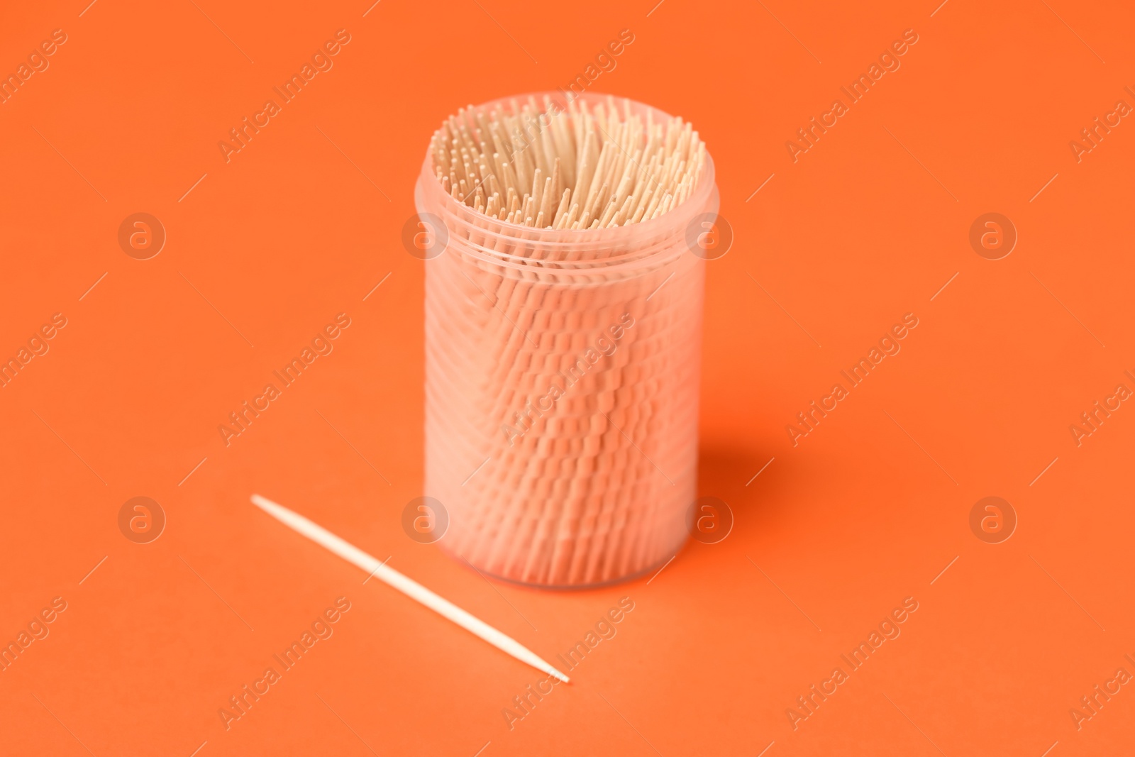 Photo of Wooden toothpicks and holder on orange background
