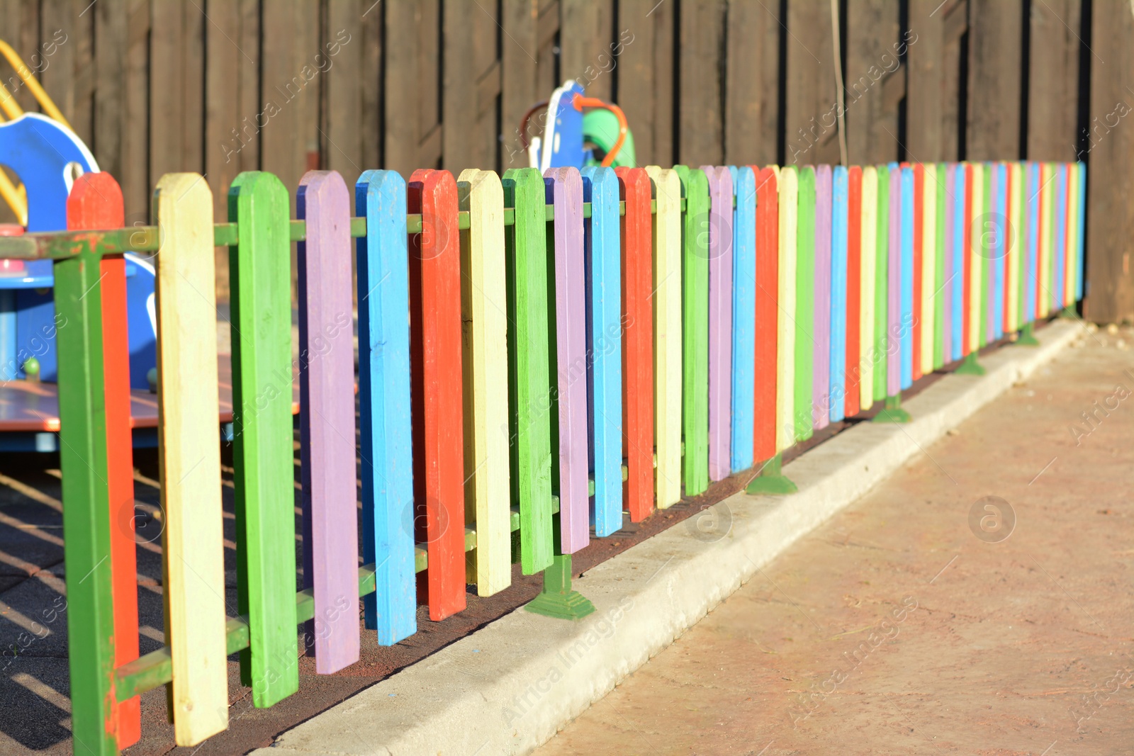Photo of Colorful wooden fence near playground on sunny day outdoors