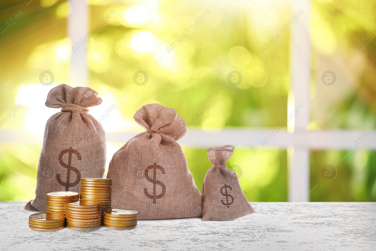 Image of Burlap bags with dollar signs and coins on white table indoors