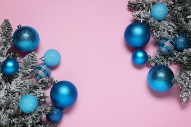 Photo of Shiny blue Christmas balls and fir tree branches with snow on pink background, flat lay. Space for text