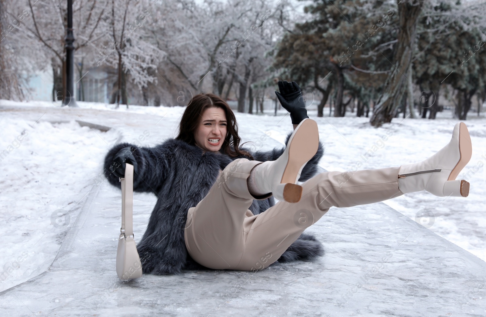 Photo of Young woman fallen on slippery icy pavement in park