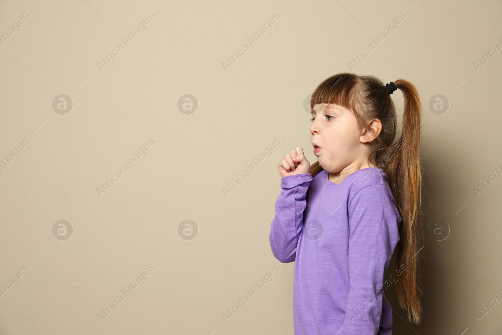 Photo of Cute little girl coughing against color background. Space for text